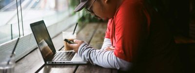 Man sitting with his laptop and phone at a coffee shop